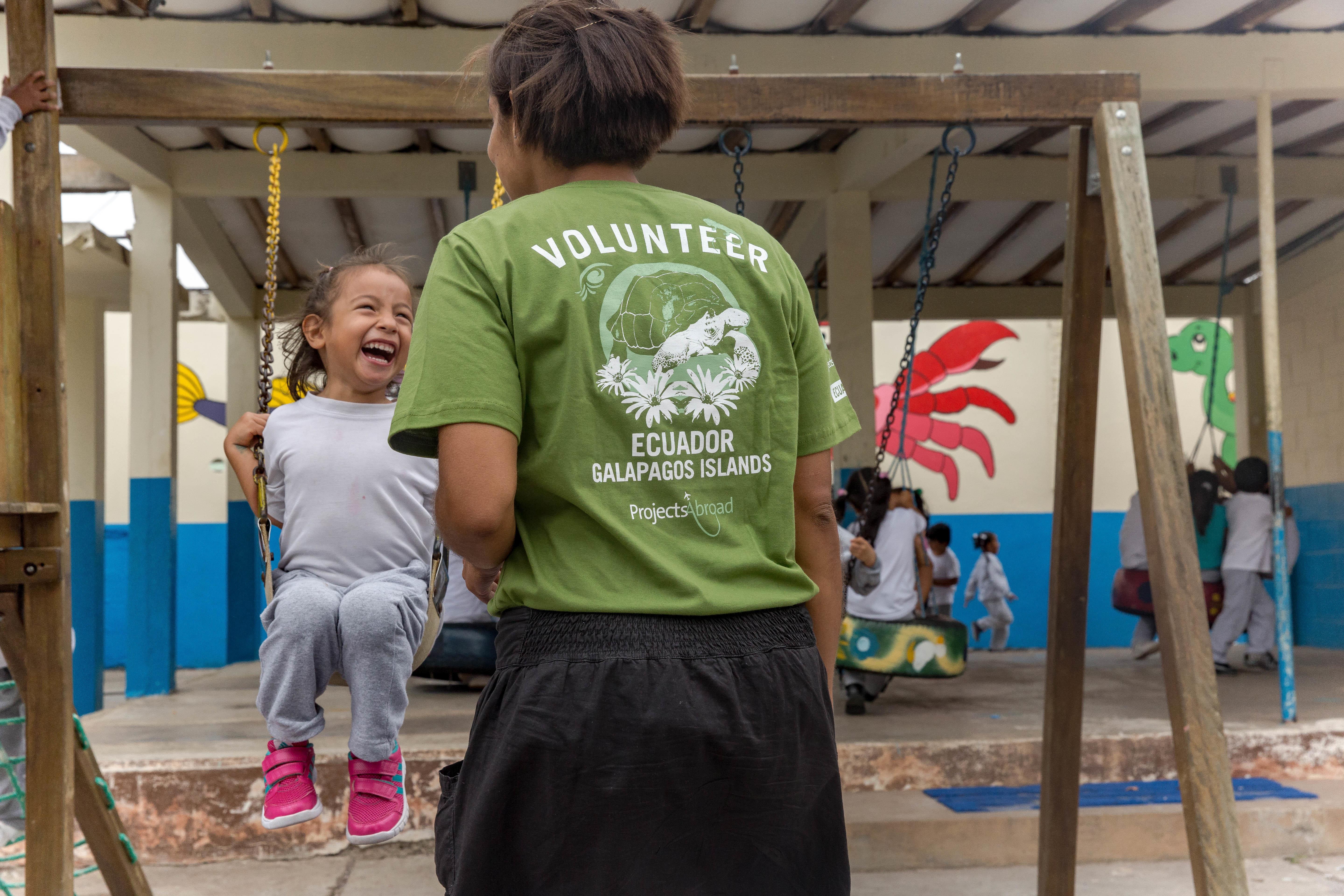 A volunteer pushes a child on a swing as part of her work in Ecuador on Projects Abroad's programme for teenagers A teenager does conservation volunteer work and works with children in the Galapagos